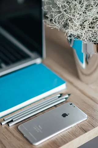 银色iPhone配蓝色笔记本和铅笔