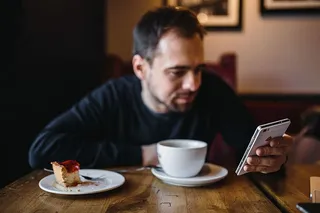 年轻的衣着优雅的男子坐在咖啡馆里