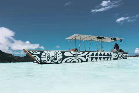 一个人坐在蓝天下的蓝白相间的船上