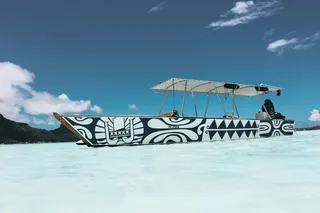 一个人坐在蓝天下的蓝白相间的船上