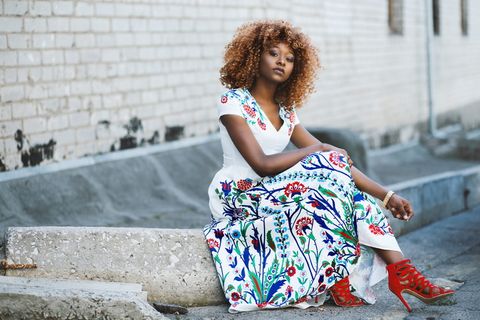 穿着红色皮带高跟鞋坐在水泥砖上的女人