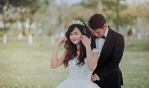 新郎将新娘的白色蕾丝婚纱系在背后