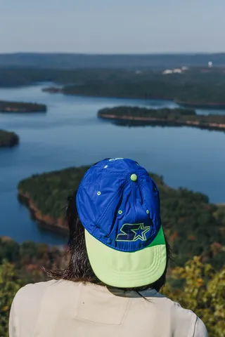 身穿白色圆领上衣和蓝绿色帽子的人站在绿岛前面