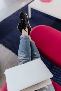 使用笔记本电脑,交叉双腿坐在沙发上的女人 使用笔记本电脑,交叉双腿坐在沙发上的女人