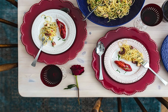精美的晚餐，搭配海鲜意大利面、小龙虾和红酒，餐桌上装饰着玫瑰