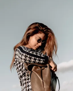 女人穿着黑色和白色的刺刺运动衬衫，看着棕色皮包