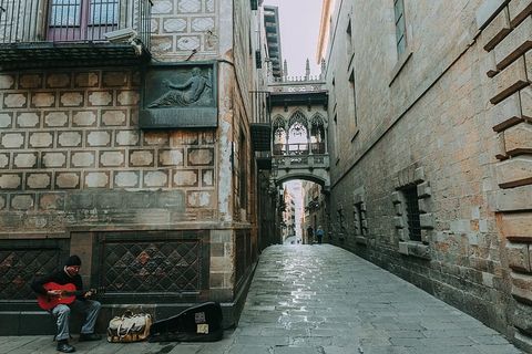 走廊旁边棕色混凝土墙边弹吉他的男人