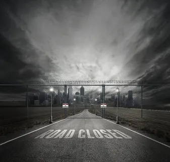 城市前面有灰色栅栏门的道路上封闭道路的灰度照片