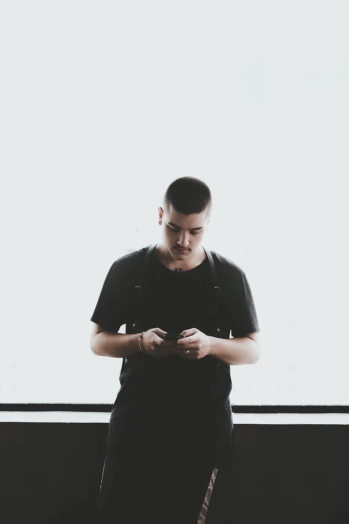 一名身穿黑色衬衫手持智能手机的男子