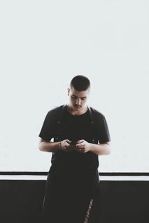 一名身穿黑色衬衫手持智能手机的男子