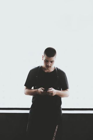 一名身穿黑色衬衫手持智能手机的男子