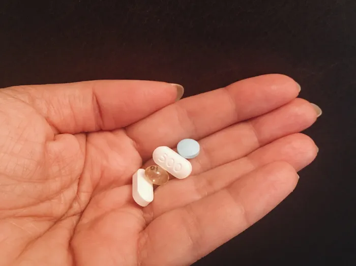 拿着四片什锦药片的人