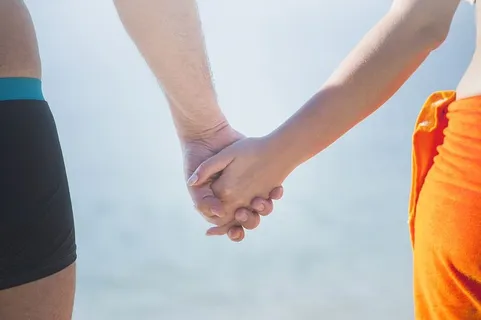 在海滩上,一对情侣手牵着手对着天空 在海滩上,一对情侣手牵着手对着天空