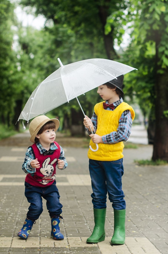 蹒跚学步的孩子拿着雨伞在女孩身边