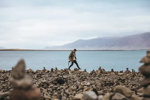 一个年轻的高加索徒步旅行者在一个山湖的石头海岸上 一个年轻的高加索徒步旅行者在一个山湖的石头海岸上