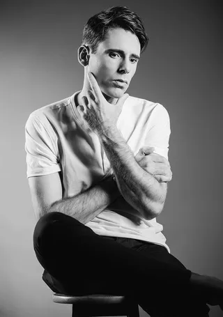 一名男子一边坐着一边触摸他的下巴