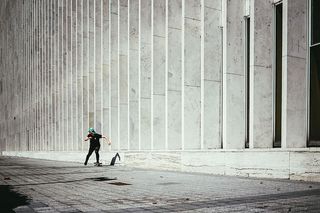 一名戴着帽子的年轻白人滑板运动员经过一座城市建筑