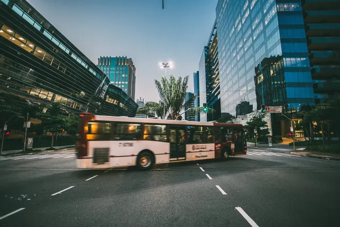 白天在高层建筑附近的道路上行驶的白色巴士