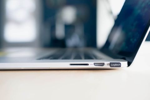带有USB、HDMI和SD卡输入的MacBook侧视图。背景模糊的木制桌子上的苹果MacBook。