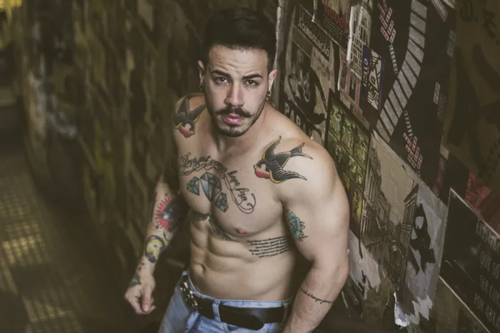 有纹身的男人站在墙边