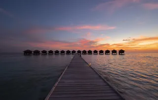 日落时水体上棕色木屋的轮廓