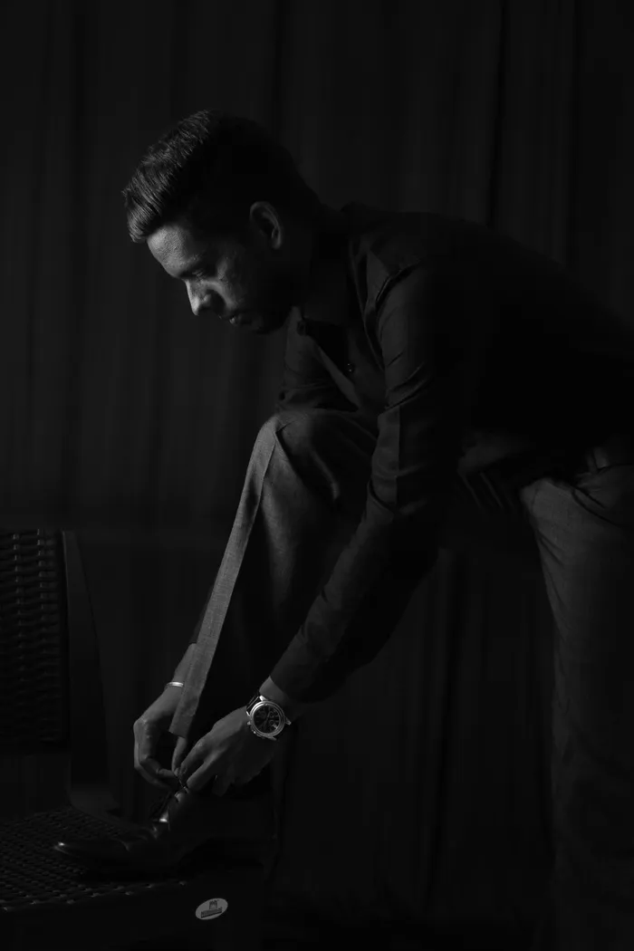 身着衬衫和裤子的男子系鞋带的灰度照片