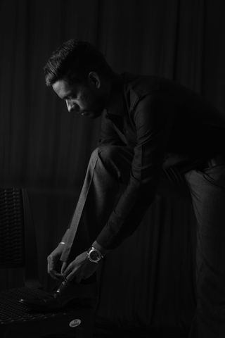 身着衬衫和裤子的男子系鞋带的灰度照片