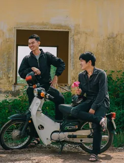 两名男子站在一辆黑白相间的摩托车旁