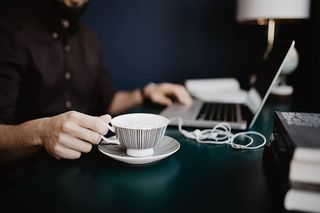 男性用笔记本电脑和一杯咖啡工作