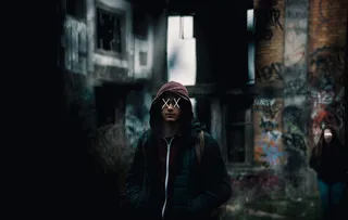 在建筑物附近穿着黑色和棕色拉链连帽衫的男子的焦点摄影