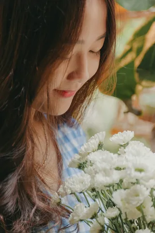 微笑的女子手持白色菊花花束