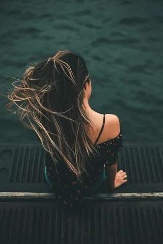 坐在黑色水面上俯瞰水体的女人