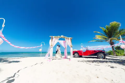 一对情侣站在海边的红色汽车旁 一对情侣站在海边的红色汽车旁