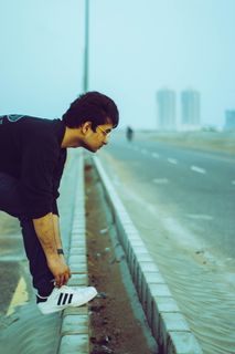 身穿黑色T恤和蓝色牛仔牛仔裤、系鞋带的男子