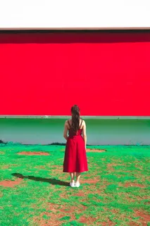 身穿红色无袖连衣裙的女子站在草地上