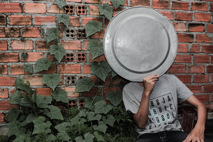 穿着灰色圆领T恤的人在砖墙旁边的脸上拿着托盘