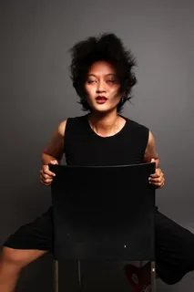 女人向后坐在灰色背景的黑色椅子上