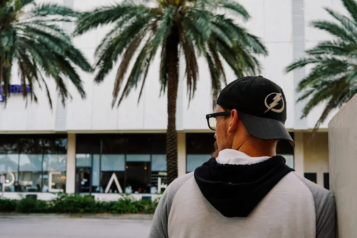 穿着黑白连帽衫和黑白按扣的男子白天在街上散步 穿着黑白连帽衫和黑白按扣的男子白天在街上散步
