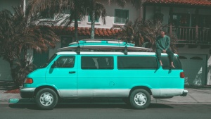 一名男子坐在停在房子附近的Teal Dodge Ram面包车上