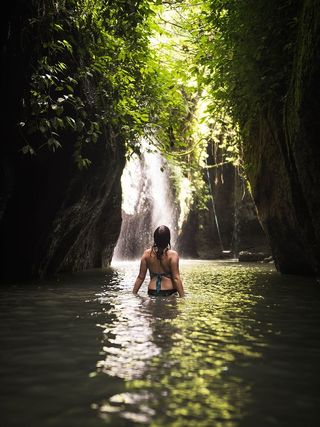 在瀑布水坑上穿着比基尼的女人