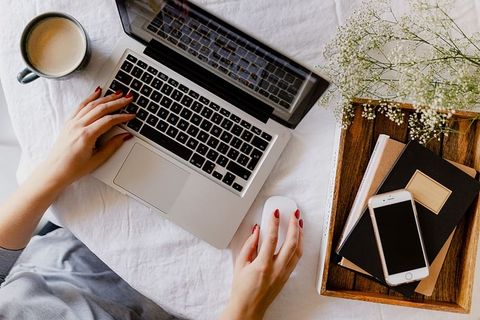 一位女士在一张桌子旁工作，桌上有一台笔记本电脑和一杯咖啡