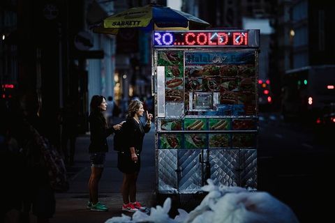 两个女人晚上在灰色食品摊上买食物