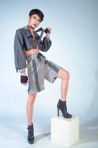 身穿灰色长袖短上衣、黑色皮革跟靴的男子