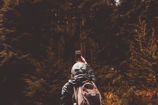 使用智能手机时站在森林前的人