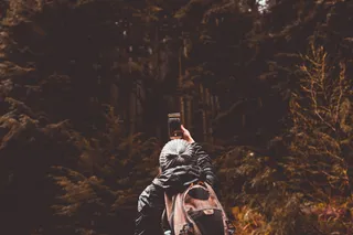 使用智能手机时站在森林前的人