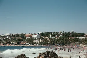 热带海滩上游客的全景，海浪拍打着海岸