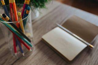 木制书桌上有彩色铅笔的笔记本