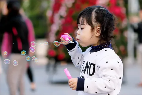 白天,一个蹒跚学步的小女孩穿着黑白毛衣,手里拿着一瓶塑料泡泡 白天,一个蹒跚学步的小女孩穿着黑白毛衣,手里拿着一瓶塑料泡泡