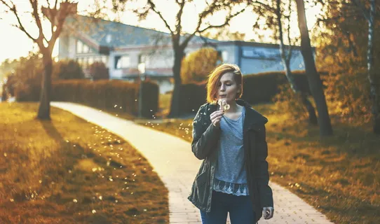 站在小路上吹蒲公英花的女人 站在小路上吹蒲公英花的女人