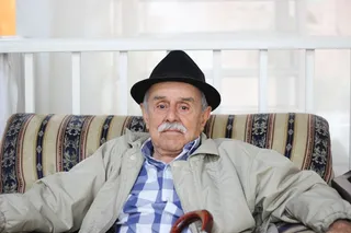 穿着灰色夹克、戴着黑色帽子的男子坐在沙发上